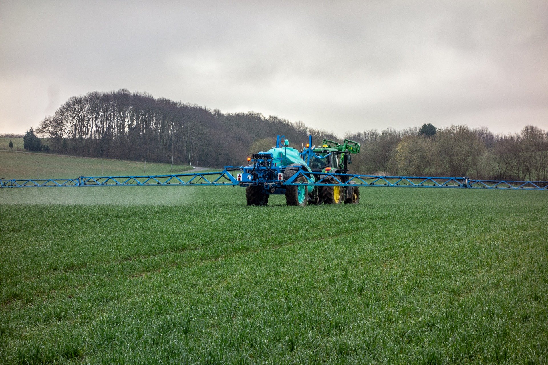 Ein landwirtschaftliches Fahrzeug fährt über Feld und düngt es mit umweltschädlichem Nitrat.