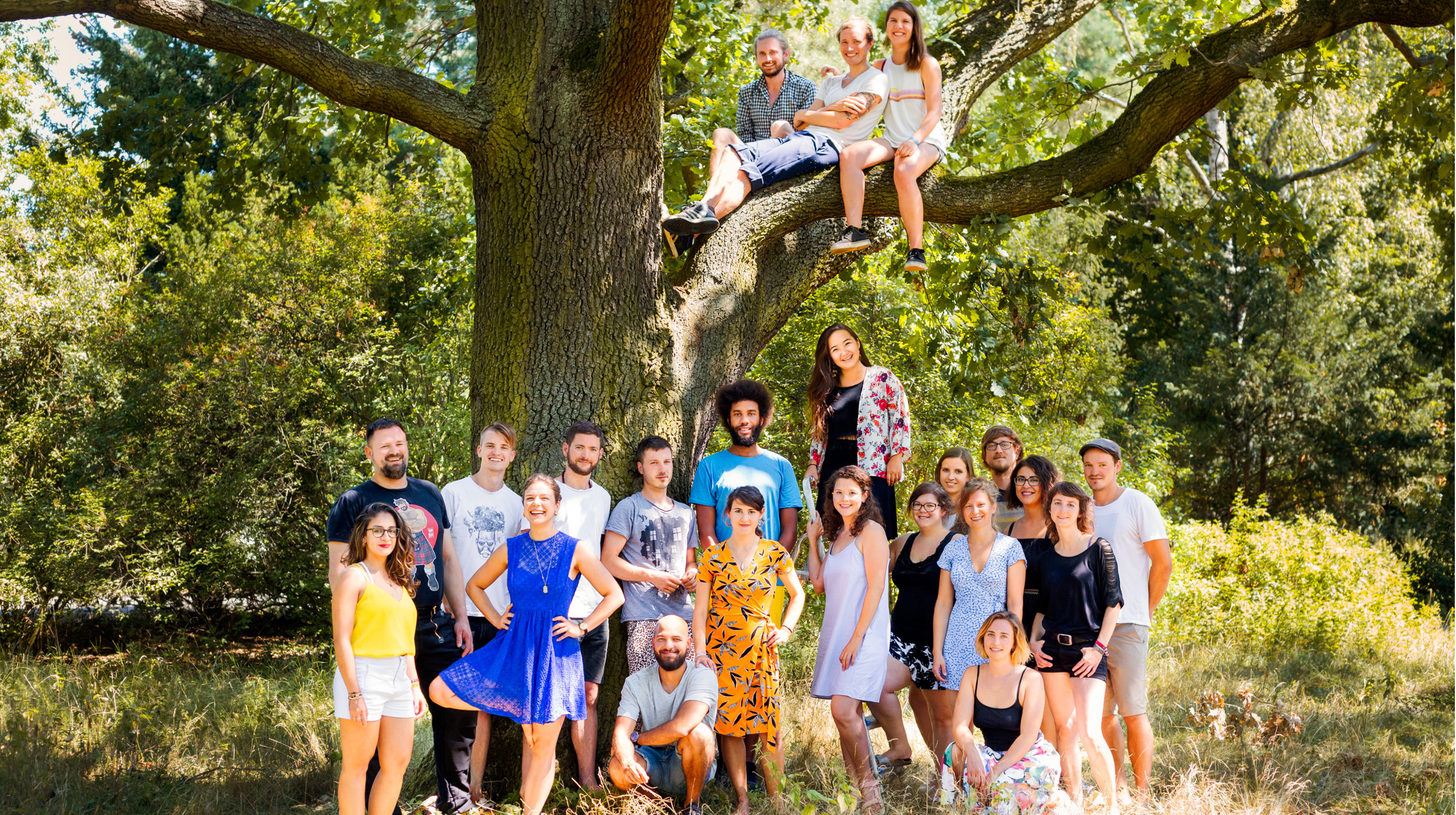 Das Bild zeigt ein Gruppenfoto der soulbottles Mitarbeitenden: 21 Menschen die im Freien vor und in einem Baum sitzen.